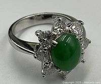 Close-up of platinum ring showing jadeite cabochon and surrounding heart-shape diamonds
