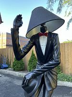 Front view of statue floor lamp showing suit, red bow tie, black conical shade