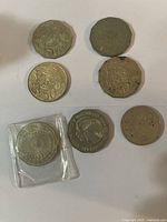 Overall view of seven coins laid out showing shapes and sizes