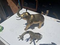 Elephant and giraffe brass figurines together on tabletop