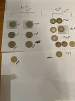 Overview of all one-dollar and 50-cent coins laid out with handwritten years