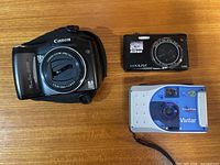 Canon, Nikon and Vivitar cameras on table