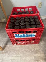 Stacked red plastic crates filled with stubby bottles
