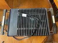 Top view of black electric grill with power cord and handles visible