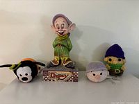 Front view of Dopey statuette flanked by Goofy and Dopey Tsum Tsums and crocheted Dopey