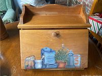 Full view of wooden breadbox with painted front and shelf