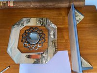 Top view of octagonal painted frame with round mirrored insert; partial view of rolled artwork and shelf