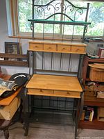 Full view of metal baker's rack showing wood drawers, shelves, glass shelf, and metal frame