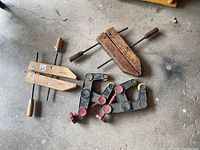 Group view of two wooden hand clamps and two plastic angle clamps on floor
