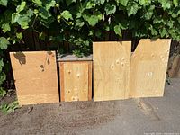 four plywood panels leaning outdoors