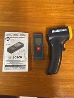 Bosch GLM 10 meter, instruction booklet, Mastercraft thermometer on table