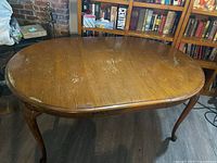 Full view of oak dining table with leaf inserted showing oval shape and surface wear