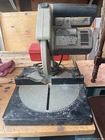 Full view of tabletop miter saw showing handle, motor housing and base