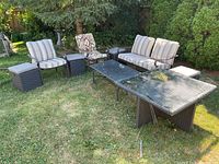 Full view of patio set showing loveseat, two armchairs, glass-top table and two ottomans