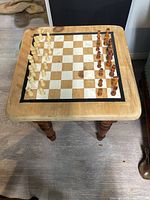 Full view of wooden table with painted chessboard and pieces arranged