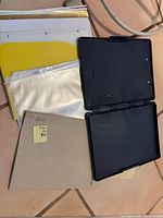 Stack of sheet protectors, yellow dividers, beige folder, open black storage clipboard