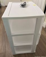 Front angled view of white three-drawer cart, bagged caster wheels on top