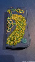 Front view showing full embroidered peacock design on wallet