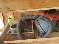 Overall view of Husky wet-dry vacuum with hose, wands, filters and nozzle in wooden cubby