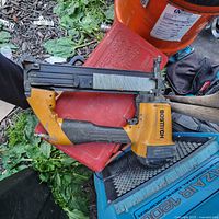 Full view of Bostitch pneumatic brad nailer placed on outdoor surfaces, showing overall condition including handle, nail magazine, and trigger area.