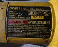 Close-up of the model and specification label on the grinder showing 'DW831 5" (125mm) angle grinder 13 amp 10,000 RPM'.