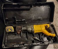 DeWalt reciprocating saw in black hard case with compartments and used condition visible on saw body and handle.