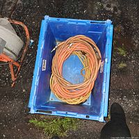 Blue crate with three coiled hoses: two orange air hoses and one yellow extension cord.