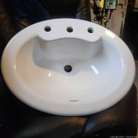 Top view of the white oval porcelain sink showing three faucet holes and smooth basin surface.