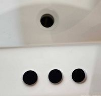 Close-up of the 3-hole faucet configuration on the flat edge of the white porcelain sink basin.