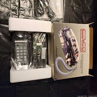 Photo of the phone in original packaging with styrofoam padding showing clear phone body and keypad