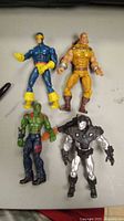 Top view of all four Marvel Legends figures laid out on white surface showing details of each.