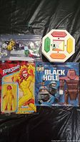 Lot contents including sealed Firestar figure, The Black Hole book, bag of dice, and electronic copy-cat game