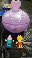 Photo showing L.O.L. Surprise doll box, Lisa Simpson and Daddy Pig figures on table