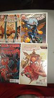 Four Amazing Spider-Man comic books laid out including 'Ends of the Earth' and 'Big Time' series with distinct cover art showing Spider-Man, Black Cat, and other characters.