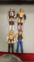 Top-down photo showing all four WWE wrestling figures lying flat on a surface