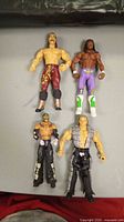 Four WWE wrestling figures arranged on a flat surface showing full-body front views.