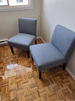 Two light blue upholstered armless chairs positioned side by side