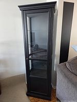 Full view of black curio cabinet showing glass door and shelves