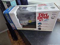 Boxed Dirt Devil handheld carpet cleaner showing front and side graphics