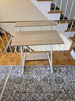 Front view of compact computer desk with laminate top, raised shelf, white metal frame