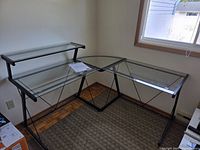 Full view of assembled L-shaped glass desk in corner