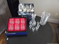 Group shot showing boxed tumblers, boxed goblets, decanter, cordial glasses, and vase