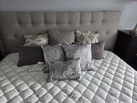 Eight throw cushions arranged on bed showing variety of patterns and colors