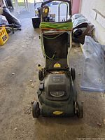 Front three-quarter view of the electric mower showing deck, wheels, handle and power cord