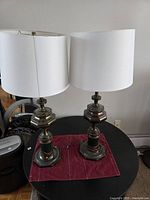 Front view of both brass lamps with shades on round table