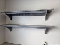 Shelves mounted on wall, side view shows brackets and hooks