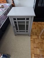 Front view of white end table showing glass door and shelf