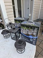 Two boxed sets of Hampton Bay solar pathway lights with lanterns on table