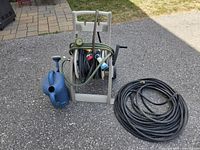 Overall lot: hose reel cart with hoses, black hose, blue watering can