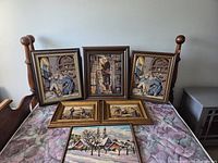 All six framed needlepoint pieces on bed